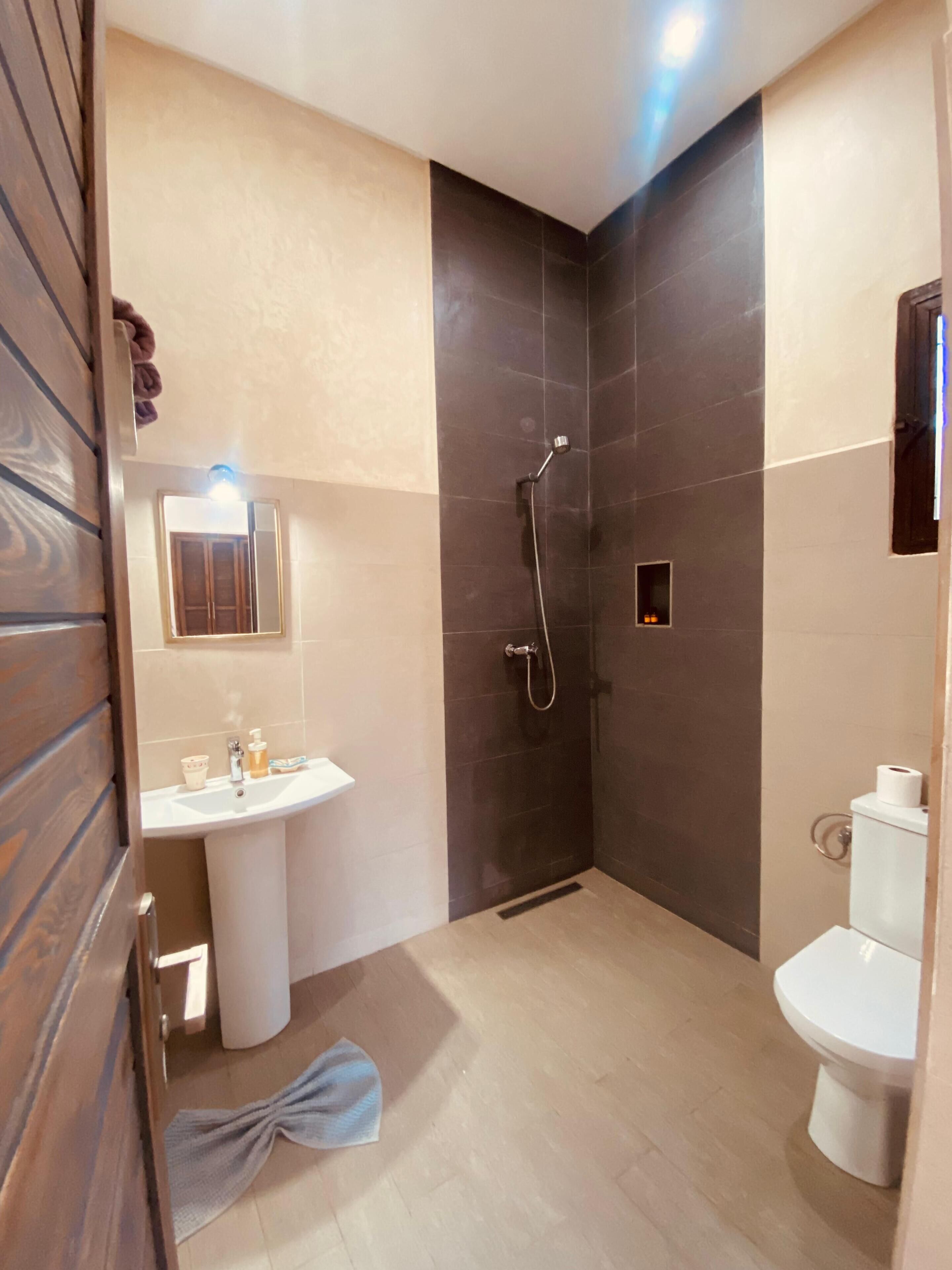 Een moderne badkamer met douche, wastafel en toilet.