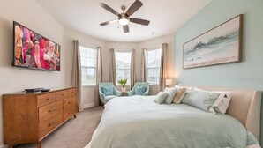 A bedroom with a bed, a dresser, a ceiling fan, a TV, and a window with curtains. - Last Minute Disney! Private Pool, Hot Tub, Game Room & Themed Bedrooms. Book Now! #47929 (Orlando)