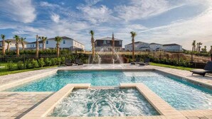 A rectangular swimming pool with a central water feature, surrounded by palm trees and a fence. - Last Minute Disney! Private Pool, Hot Tub, Game Room & Themed Bedrooms. Book Now! #47929 (Orlando)