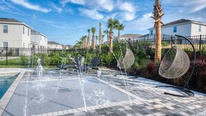 Un'attrazione acquatica con più fontane, circondata da una zona pavimentata a scacchi.