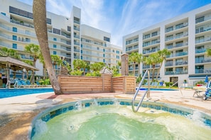 Zona de piscina de hotel con jacuzzi, sillas de descanso y terraza de madera.