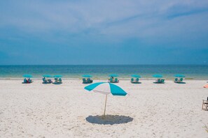 Una playa con múltiples sombrillas turquesa y sillas de descanso.