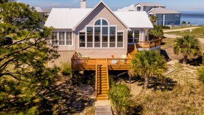 A coastal house with a large deck, a covered porch, and a view of the ocean. - At Ease - 535 Barcelona 3 Bedroom Home by RedAwning (Dauphin Island)