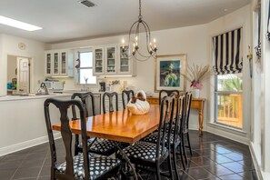 A dining area with a wooden table and chairs, a chandelier, and a view of the outdoors.