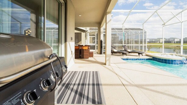 Un espace extérieur abrité comprenant un barbecue, une piscine et des chaises longues.