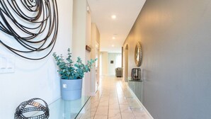 Un couloir moderne avec une table en verre, une plante en pot et un motif en spirale décoratif sur le mur.