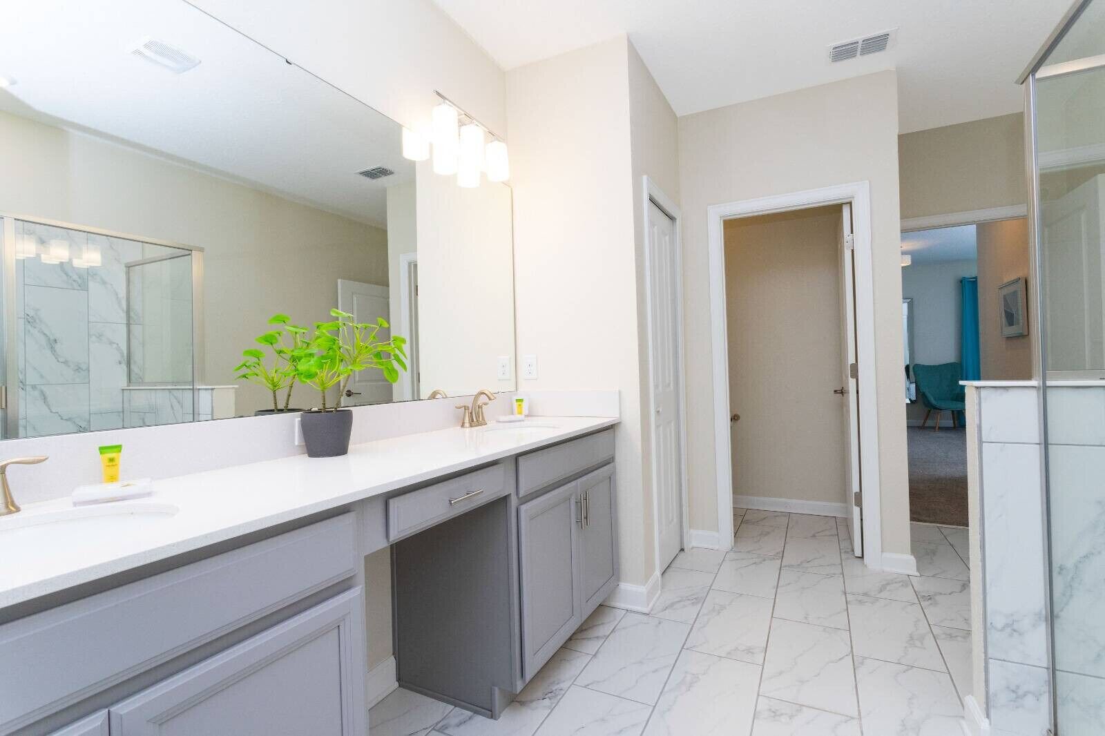 Un baño moderno con un espejo grande, un lavabo y una planta en maceta.