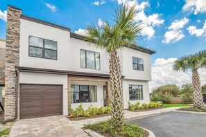 A modern two-story house with a garage, large windows, and a well-maintained garden with palm trees. - Last Minute Disney Getaway! Luxury Villa with Private Pool. Book Now! #57975 (Orlando)