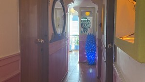 A hallway with a wooden door, a mirror, and a blue decorative object. - Can Butik Pansiyon (Çesme)