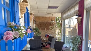 A covered outdoor seating area with wicker furniture and blue accents. - Can Butik Pansiyon (Çesme)