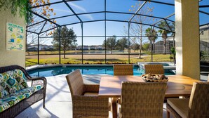 A pool area with wicker furniture, a pool rule sign, and a view of a residential area. - Last Minute Disney Getaway! Private Pool, Hot Tub & Game Room. Book Now! #60493 (Orlando)