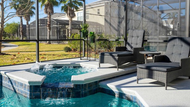 A covered outdoor swimming pool with a hot tub, surrounded by wicker furniture and a view of palm trees and a house. - Last Minute Disney Getaway! Private Pool, Hot Tub & Game Room. Book Now! #60493 (Orlando)