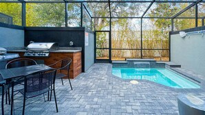 An outdoor patio with a grill, seating, and a small pool.