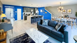 A modern living room with a sofa, coffee table, and a dining area with a table and chairs.