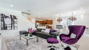 Un salon moderne avec un canapé, un fauteuil, une table basse et des œuvres d’art accrochées au mur.