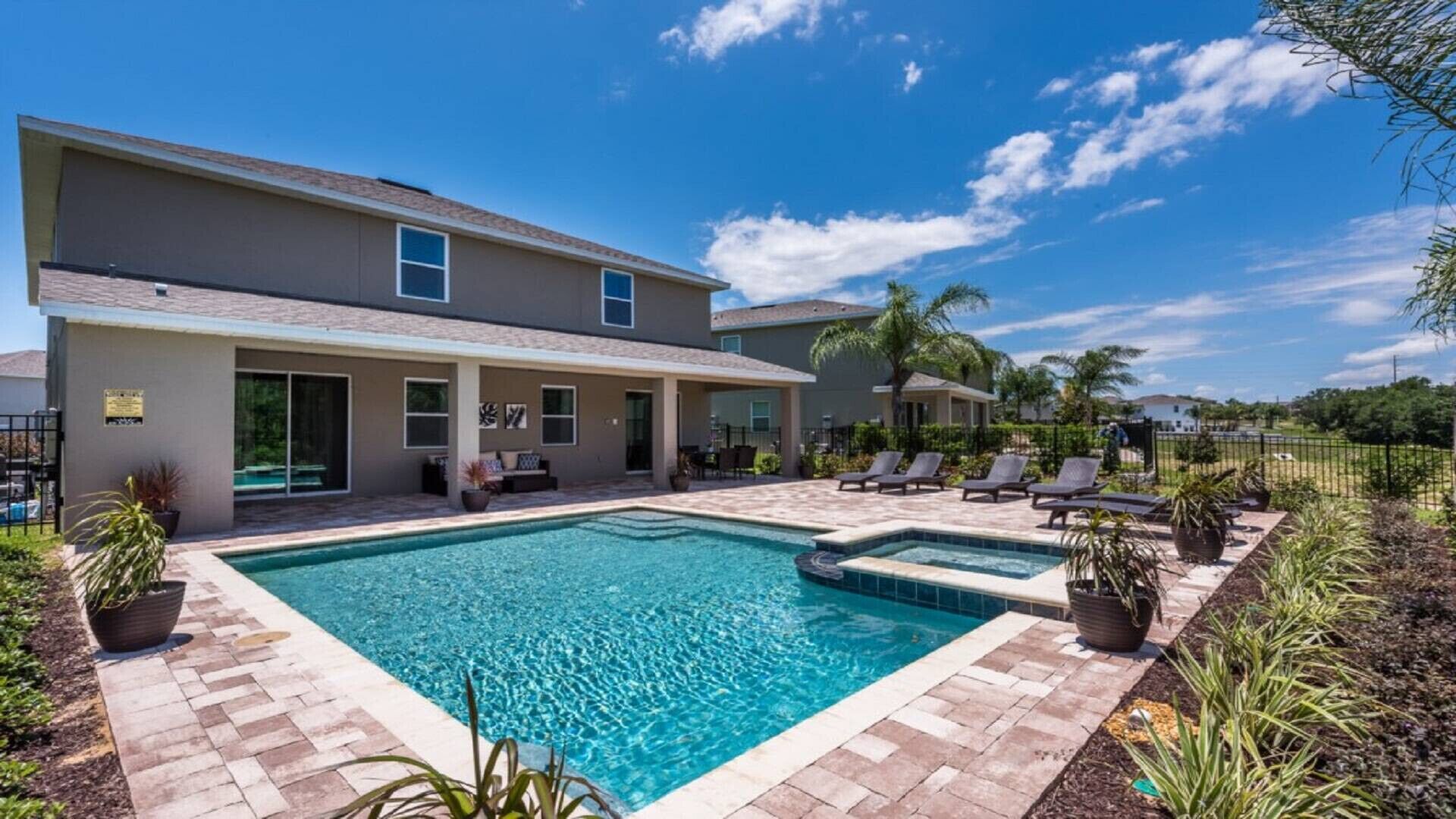 A two-story house with a swimming pool, outdoor seating, and a fenced yard.