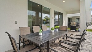 Un patio con mesa y sillas, una parrilla y plantas en macetas.