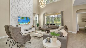 Un salón amplio con una televisión grande, asientos cómodos, una mesa de centro y vistas amplias por un ventanal.