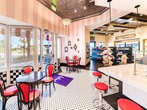 A restaurant with a checkered floor, red chairs, and a bar area.