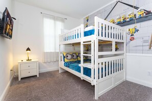 A bunk bed room with a white wall, a nightstand, and a lamp.