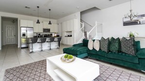 A modern living room with a green sofa, white coffee table, and patterned rug. - Last Minute Disney Getaway! Private Pool & Themed Bedrooms. Book Now! #77303 (Davenport)