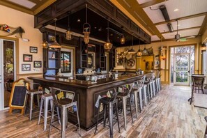 A bar area with a long counter, multiple stools, and hanging pendant lights. - Last Minute Disney Getaway! Private Pool & Themed Bedrooms. Book Now! #77303 (Davenport)
