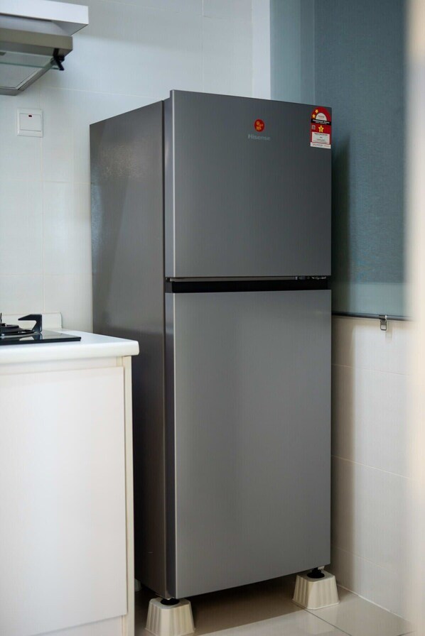A compact, modern kitchen with a built-in refrigerator, a small countertop, and a wall-mounted light fixture.