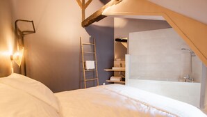 A bedroom with a bed, a ladder, a bathroom with a bathtub, and a shelf with toiletries. - Le Coursarlon (Bourges)
