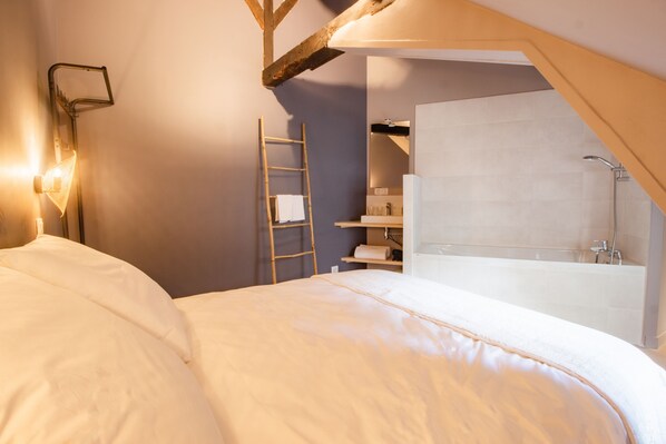 A bedroom with a bed, a ladder, a bathroom with a bathtub, and a shelf with toiletries. - Le Coursarlon (Bourges)