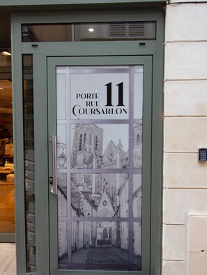 A door with a glass panel displaying a building facade and the text "Porte Rue Coursarlon 11". - Le Coursarlon (Bourges)