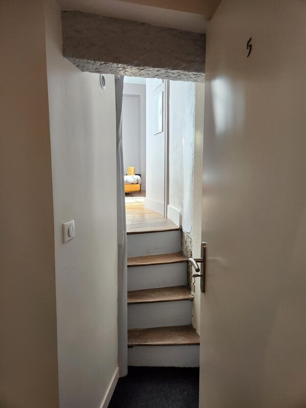 Una escalera estrecha que conduce a un dormitorio con cama y ventana.