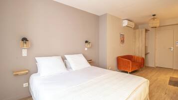 A bedroom with a bed, a chair, an air conditioning unit, and a door.