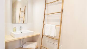 A bathroom with a white sink, mirror, and a wooden towel rack.