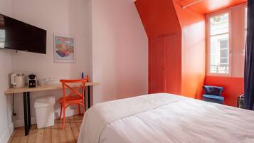 Un dormitorio con cama, escritorio, silla, televisor y ventana.