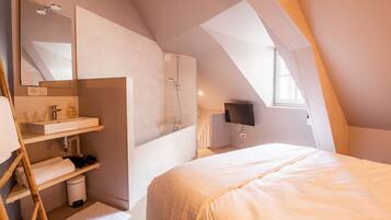 Una camera da letto con un letto grande, un bagno con vasca e vasca da bagno, una televisione e un lucernario.