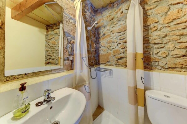 A bathroom with a stone wall, a white sink, and a toilet.