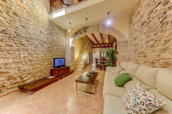 A stone-walled living room with a sofa, coffee table, and TV.