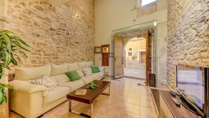 Una sala de estar con pared de piedra, un sofá, una mesa de centro y un televisor.