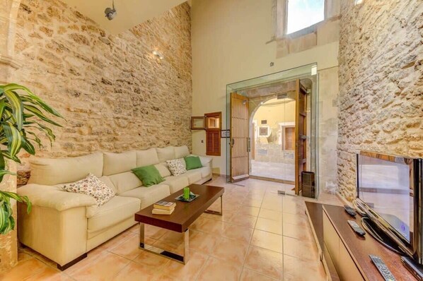 Una sala de estar con pared de piedra, un sofá, una mesa de centro y un televisor.