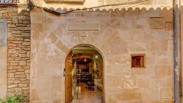 Un arco de entrada a una habitación con piso de baldosas y puerta de madera.