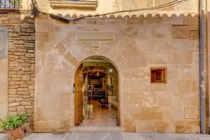 An arched doorway leading into a room with a tiled floor and a wooden door.