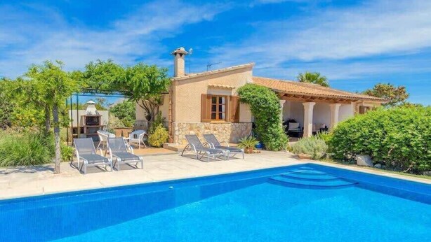 A poolside villa with a stone facade, a tiled roof, and a clear blue sky. - Villa Viva Pollenca - Beautiful Stone built mallorcan villa (Pollenca)