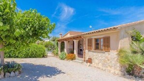 A Mediterranean-style house with a stone facade, a tiled roof, and a gravel driveway. - Villa Viva Pollenca - Beautiful Stone built mallorcan villa (Pollenca)