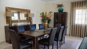 A dining area with a wooden table and chairs, a large mirror, and a vase with flowers. - Villa Selena - Beautiful Luxury villa with massage baths (Quinta do Lago)