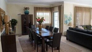 A dining area with a table and chairs, a sofa, and a cabinet. - Villa Selena - Beautiful Luxury villa with massage baths (Quinta do Lago)