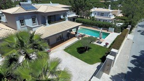 A large house with a swimming pool, surrounded by a well-maintained lawn and palm trees. - Villa Selena - Beautiful Luxury villa with massage baths (Quinta do Lago)