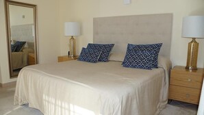 A bedroom with a large bed, two bedside tables with lamps, a mirror, and a headboard. - Villa Selena - Beautiful Luxury villa with massage baths (Quinta do Lago)