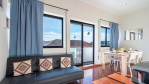 Un moderno salón con sofá, mesa de comedor y grandes ventanales con vistas a la ciudad.