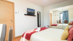 Una habitación de hotel con una cama, un televisor en la pared, un espejo y una puerta.