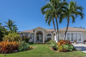 A residential house with a well-maintained lawn, palm trees, and a clear blue sky. - Walk to Beach! Family Retreat! (Marco Island)